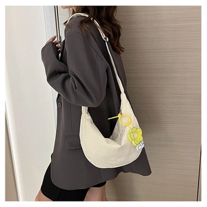 Détail du sac demi-lune blanc avec une breloque tournesol jaune suspendue