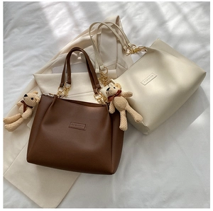 Close-up of PU leather tote bag details with FASHION logo and cute bear charm
