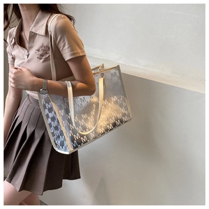 Detail of transparent PVC tote bag with letter M print and white leather handles
