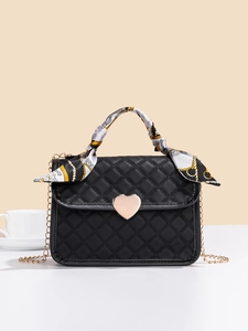 Dettaglio borsa trapuntata nera con fibbia a cuore dorata e foulard in seta decorativo