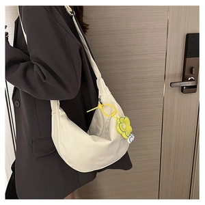 Détail d'un sac à bandoulière blanc en demi-lune avec un pendentif fleur jaune