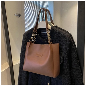 Detailed shot of brown faux leather tote bag with FASHION embossed logo and chain handle