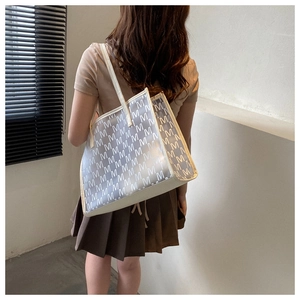 Detail of a large cream tote bag with semi-transparent M-pattern and long shoulder straps