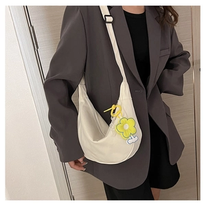 Détail du sac hobo blanc cassé avec pendentif fleur sur mannequin en blazer gris