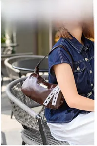 Detail of dark brown PU leather underarm bag with white heart lace and gold metal hardware