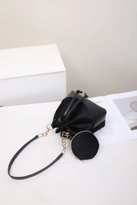 Detail of black patchwork bucket bag with gold chain strap and mini round coin purse