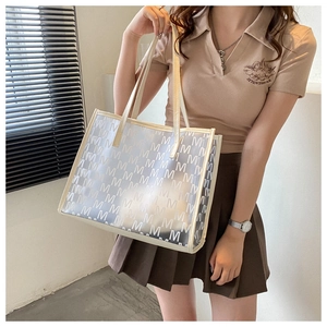 Detail of transparent PU tote bag with repeat M pattern and cream leather handles