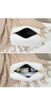 Vue détaillée de la trousse de maquillage en peluche blanche avec fermeture éclair dorée