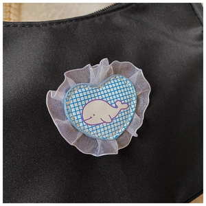 Detail einer schwarzen Stofftasche mit Spitzenherz-Patch und weißem Wal-Motiv