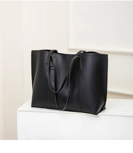 Close-up of minimalist black leather tote bag with fine stitching and thin handles