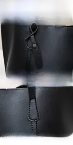 Detail showing knotted handle and precise stitching on black litchi pattern leather tote
