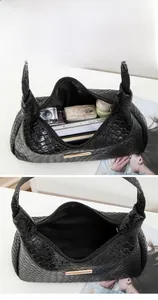 Vue intérieure du sac à bandoulière tressé noir montrant un grand espace de rangement