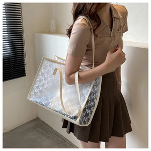 Detail of semi-transparent PU tote bag with white letter pattern and cream shoulder straps