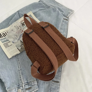 Brown faux shearling mini backpack with adjustable straps on denim jacket background