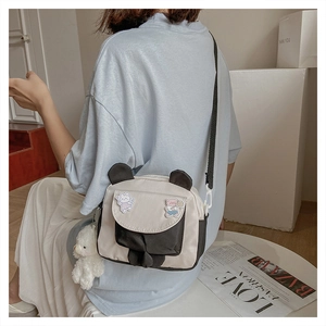 Detail of canvas crossbody bag with cute panda ears and plush bear charm on a model