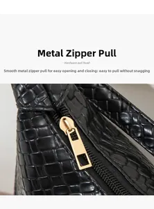Détail de la fermeture éclair dorée lisse sur sac bandoulière en cuir tressé noir