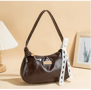 Macro detail of glossy dark brown crescent bag with white lace heart ribbon decor