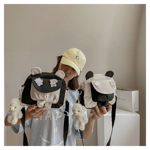Detail of cute bear-eared canvas crossbody bag with cartoon embroidery and plush pendant