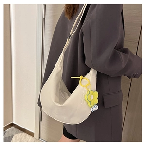 Gros plan d'un sac à bandoulière blanc en demi-lune avec un pendentif fleur jaune