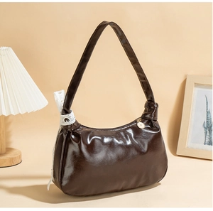Detail of dark brown hobo bag featuring a knotted strap and white lace ribbon accents