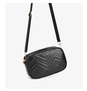 Close-up of black quilted camera bag with V-shaped stitching and gold hardware