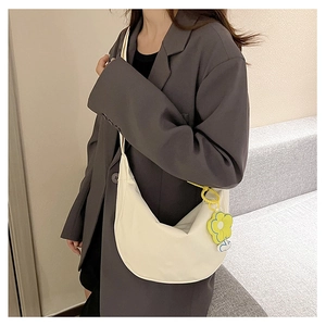 Sac à bandoulière blanc en demi-lune avec pendentif fleur jaune sur un mannequin en costume