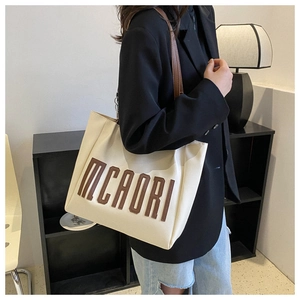 Détail du sac cabas crème avec lettrage MCAORI marron et bandoulières élégantes