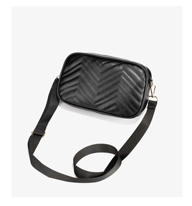 Detail of black chevron quilted camera bag with golden hardware and wide strap