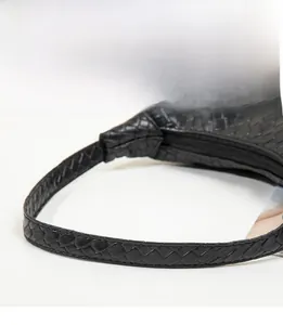 Détail de la texture tressée et de la large bandoulière d'un sac à main noir