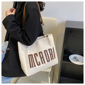 Détail du grand cabas blanc avec logo MCAORI, chaîne argentée et bandoulière marron