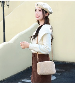 Détail d'un sac bandoulière en peluche beige avec crochets dorés et sangle en cuir