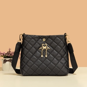 Détail du sac seau noir matelassé avec breloque flamant rose dorée et large bandoulière