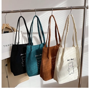 Dettaglio di quattro borse tote in velluto a coste colorate con ricami di orsetti