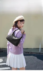 Détail de la texture tressée noire du sac hobo avec une plaque de logo argentée