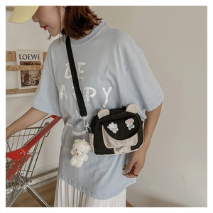 Detail of canvas crossbody bag with bear ears, plush charm and cartoon patches on flap