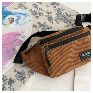 Detailed macro view of the brown corduroy fabric texture and dual zipper compartments