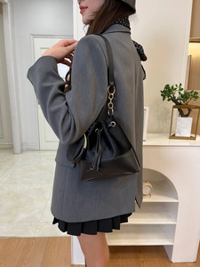Detail of black leather drawstring bucket bag with gold-tone hardware and mini round pouch