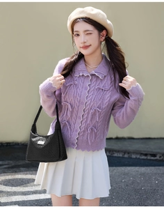 Gros plan du sac bandoulière tressé noir avec cardigan violet à nœuds en maille