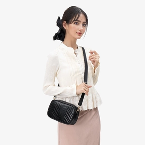 Quilted black crossbody bag with chevron pattern and wide strap on a female model