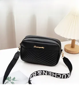 Detail of black quilted camera bag with V-pattern stitching and wide logo strap