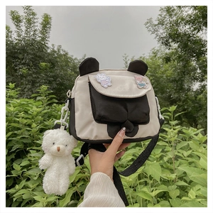 Detail of canvas crossbody bag with cartoon animal patches and plush bear pendant