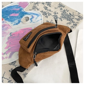 Detail view of brown corduroy waist bag with dual zippers and woven fashion label