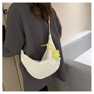 Vue détaillée du sac demi-lune blanc avec une décoration de breloque tournesol jaune