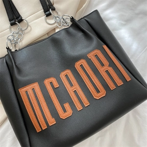 Sac cabas en cuir noir avec écusson MCADRI orange et détails de bandoulière argentée