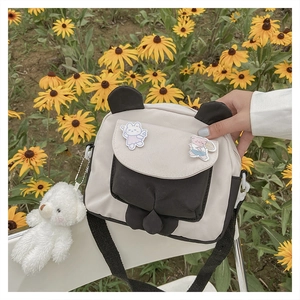 Close-up of panda canvas crossbody bag with cute badges and white bear plush keychain