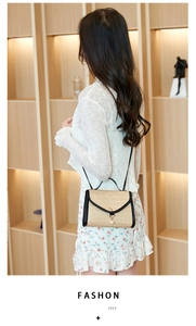 Detailed shot of beige straw crossbody bag with pearl charm and black trim on model