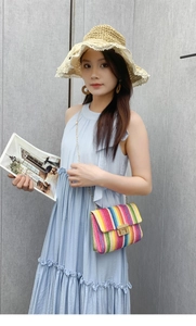 Detail of colorful woven straw bag with gold chain strap and metallic twist lock