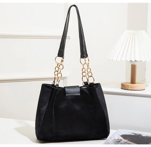 Close-up of black suede tote bag with gold chain strap and leather buckle detail
