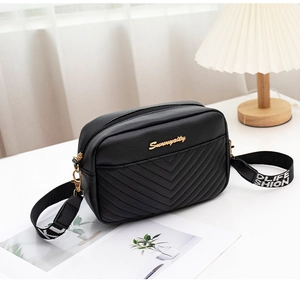 Detail shot of black PU camera bag with V-quilted pattern and wide patterned strap