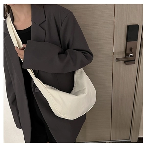 Détail d'un sac bandoulière beige en toile porté avec un blazer gris sophistiqué
